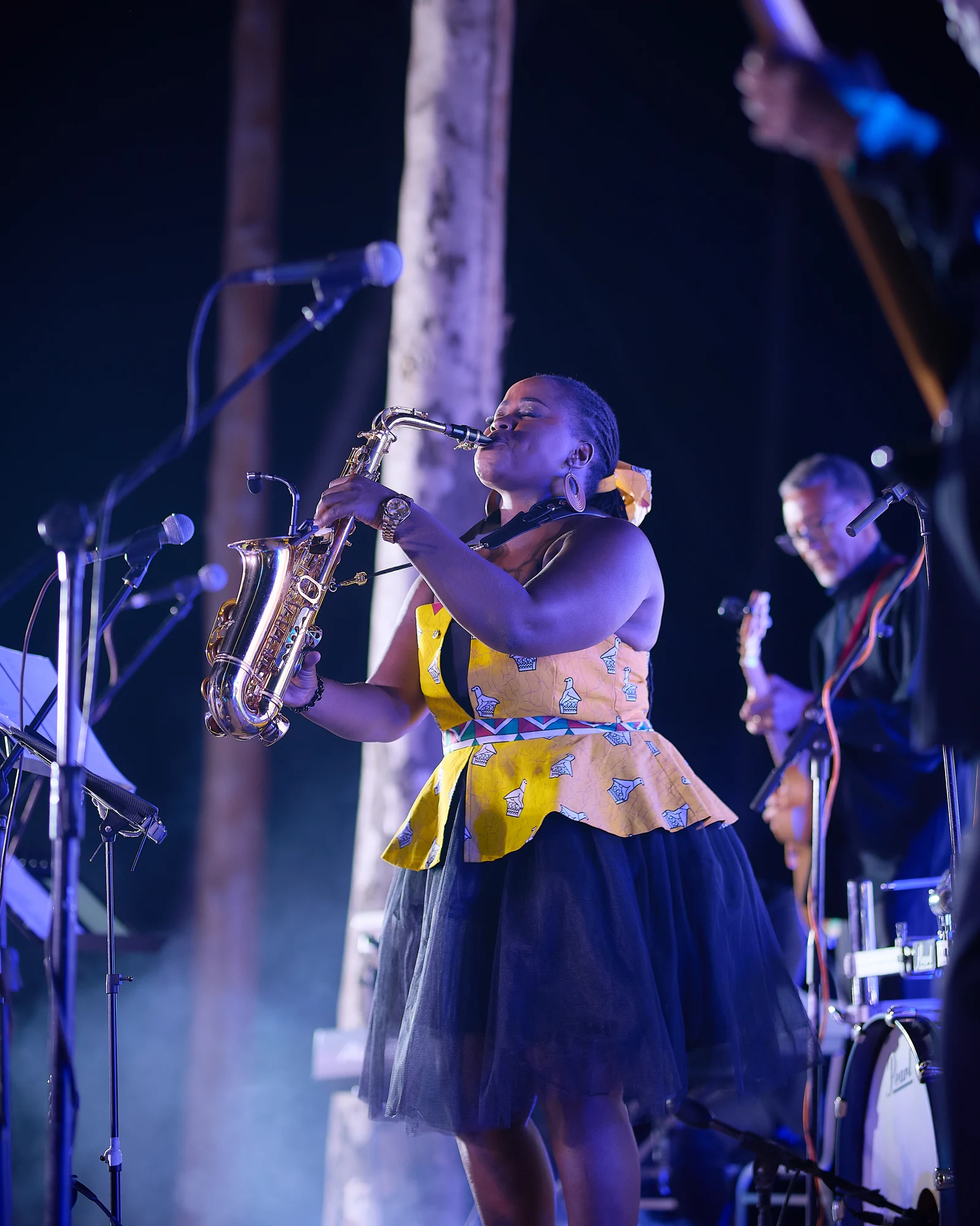 Tina Watyoka playing saxophone under blue stage lights